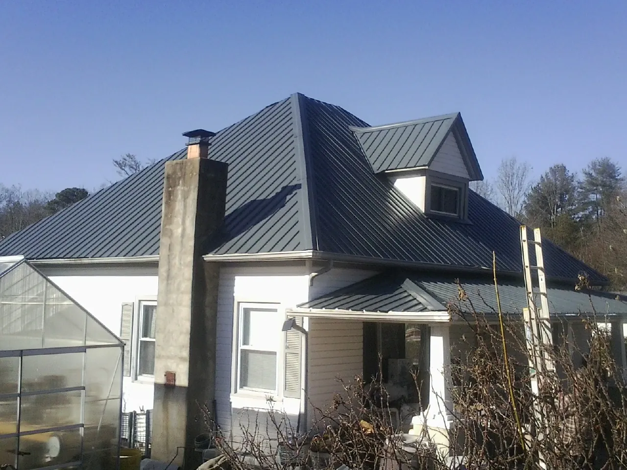 Dark blue standing seam metal roof on a white farmhouse with dormer — Slate & Tile Roof Repair by Roofing Brothers in Fielding