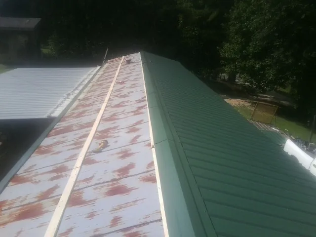 Old rusted panels beside newly installed green metal roofing — Wind Damage Roof Repair by Roofing Brothers in Fielding