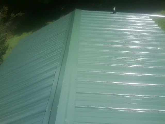 New green metal panels meeting at the ridge of a roof — Flat Roof Repair work by our crew in Fielding