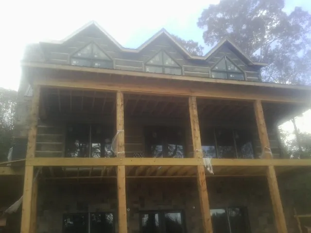 Dormers and porch framing on a large log home under construction — Roof Coating work by our crew in Fielding