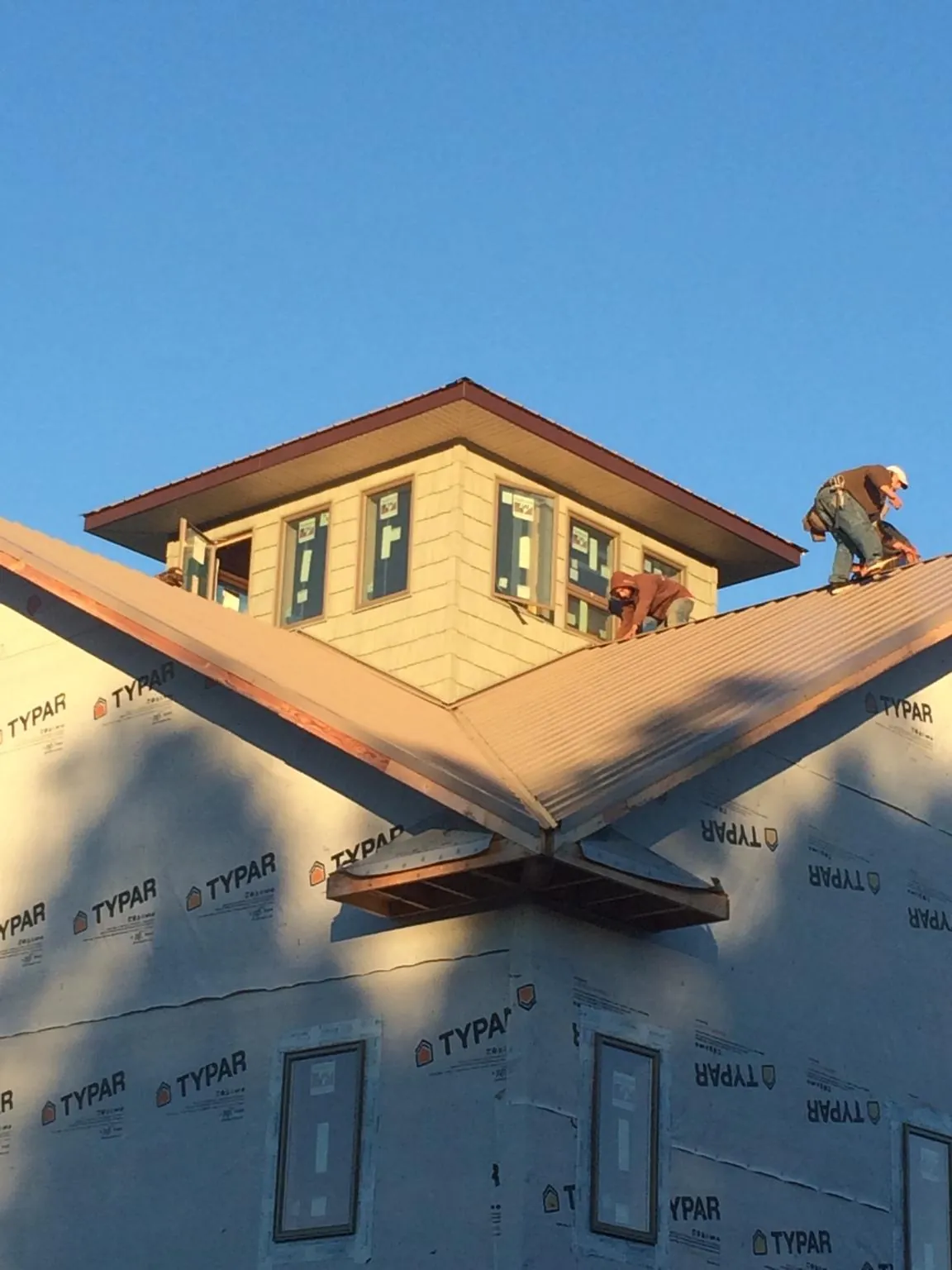 Roofers working around a rooftop cupola on a new metal roof at sunset — Roof Waterproofing in Fielding by Roofing Brothers